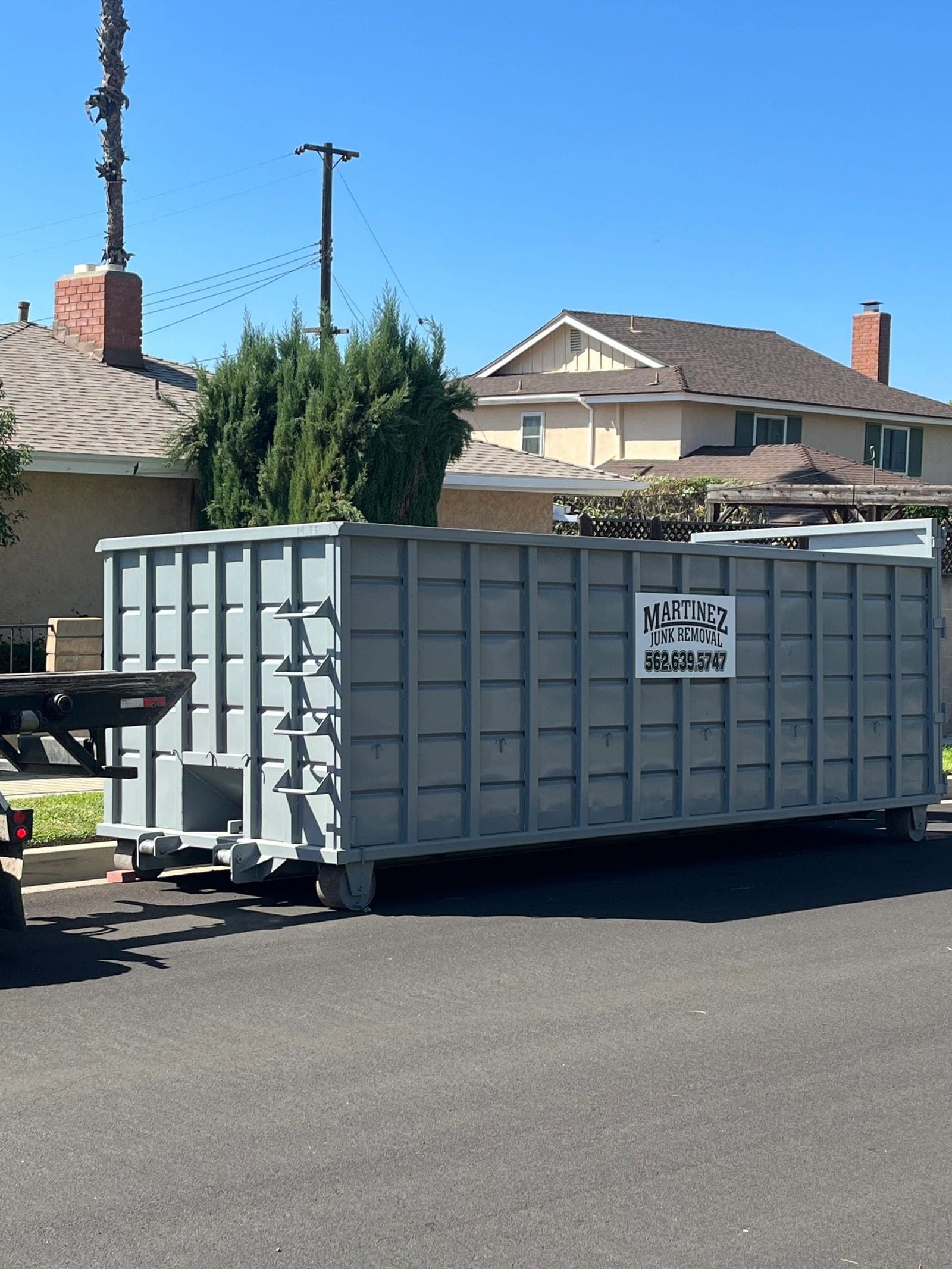 Martinez Junk Removal roll-off dumpster staged for delivery on a residential street in Chino, CA